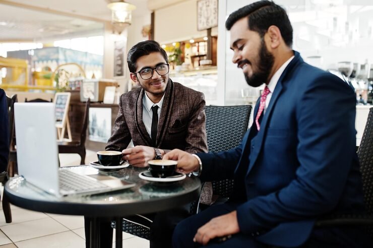 two indian business man suits sitting office cafe looking laptop drinking coffee 627829 1501